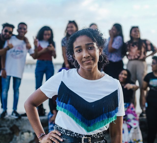 square-jibarofoto-group Smiling young woman standing in front of a group of friends outdoors
